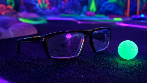 Black-rimmed 3D glasses and glowing golf ball on the course