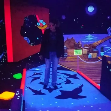 Guest playing in the glowing pirate and night sky world at Imagine 3D Mini Golf