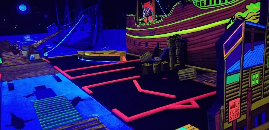 Glowing pirate ship and dock in the blacklight mini golf world