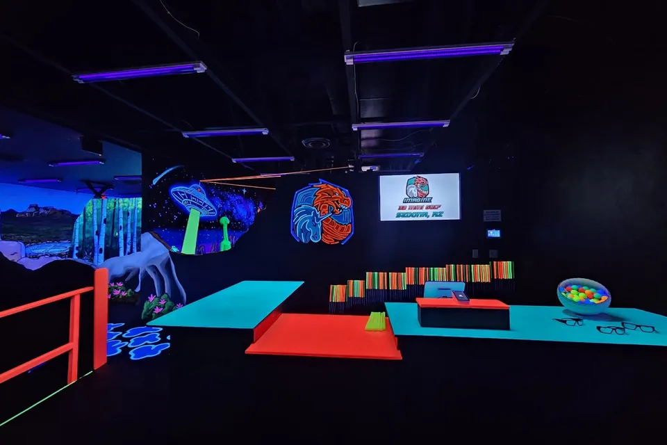 Glowing Sedona course entry with putters, balls, and blacklight murals